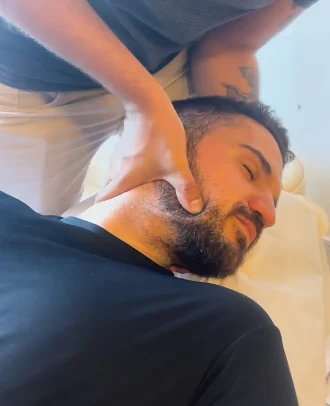 Fisioterapeuta apoiando a cabeça e o pescoço de um paciente deitado