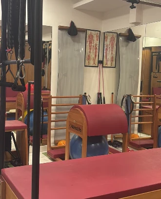 Estúdio de pilates com aparelhos e cadeiras de madeira